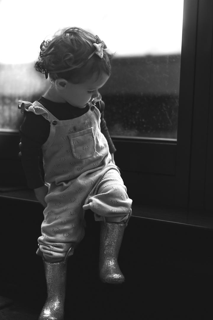 My daughter looking out a rainy window, reflecting curiosity and the cozy atmosphere of a rainy day.