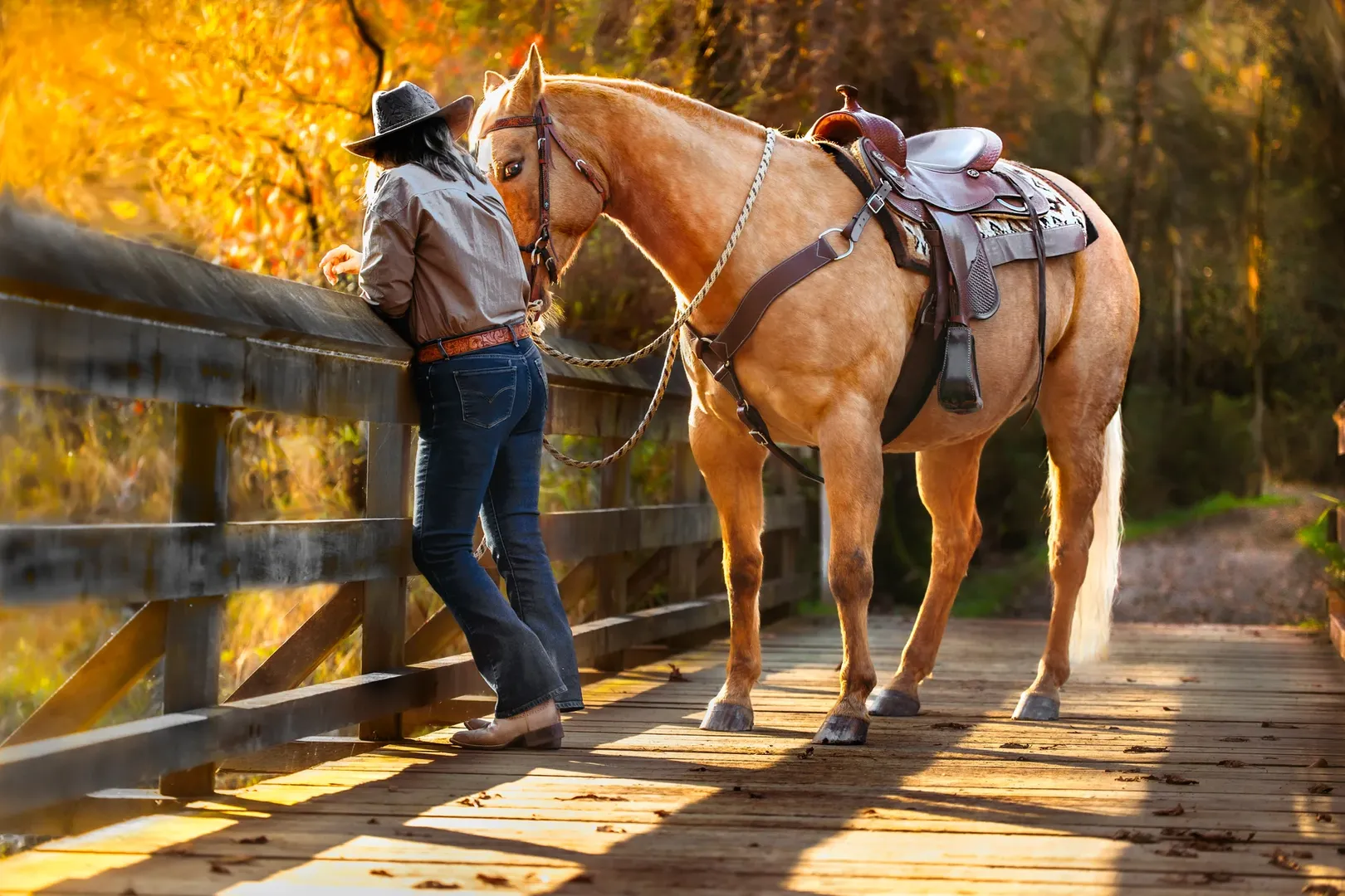 Woman riding a bay horse through forest during equine portrait session.